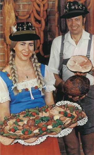 woman and man holding sausages and hams